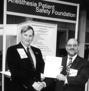 Durante la reunión anual de la ASA en 2001, en el puesto de la APSF, John Eichhorn, MD (izquierda), editor fundador del Boletín informativo, le entrega las últimas galeradas y le desea lo mejor a Robert Morell, MD, quien lo sucederá como editor.