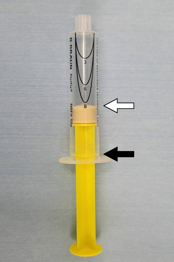 Figure 1. When the plunger is pulled back to the stop (black arrow), the plunger tip is located at the numeral 8 (white arrow).